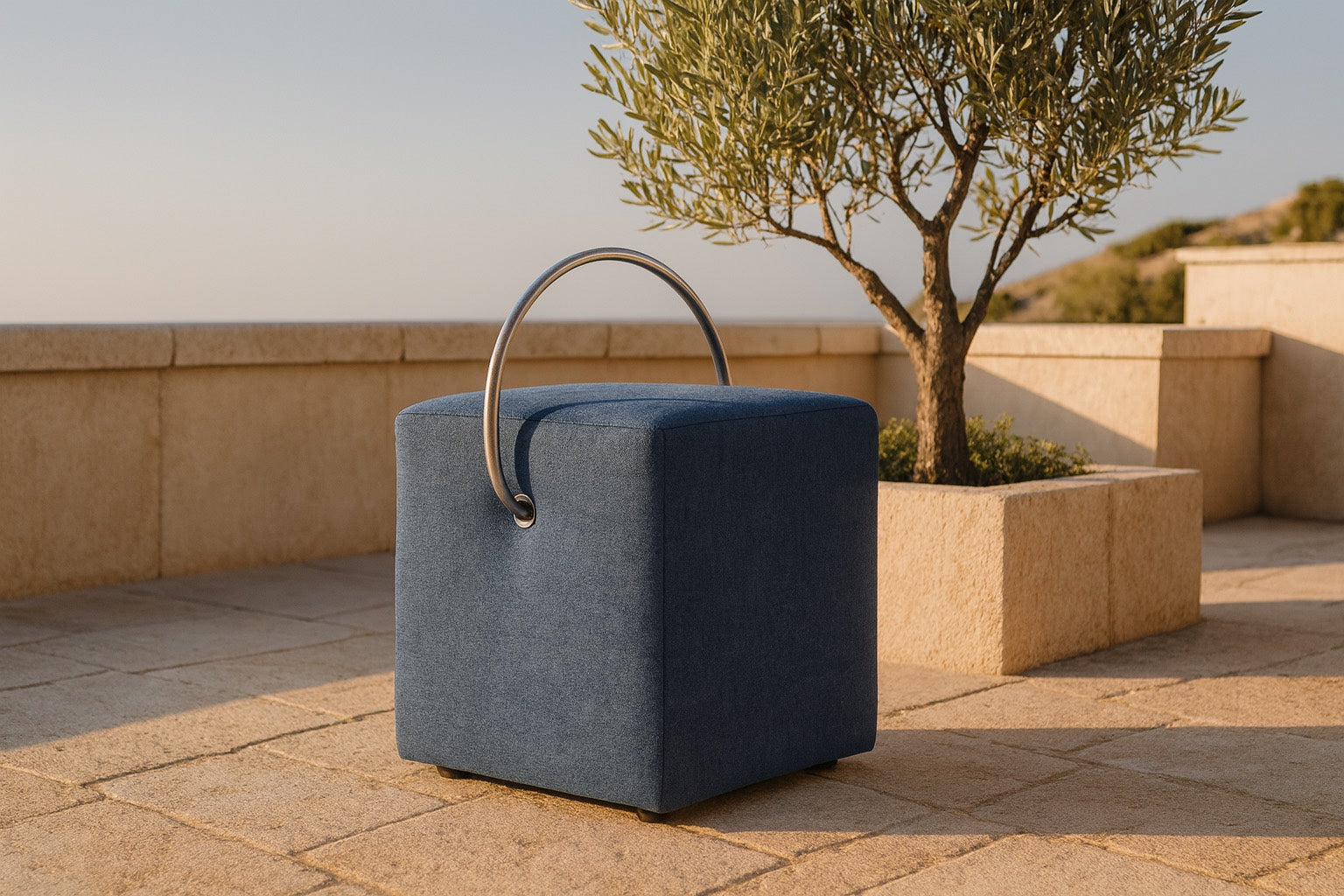 Blauer Designhocker von Hockerhelden mit Tragegriff auf Natursteinterrasse im Außenbereich.