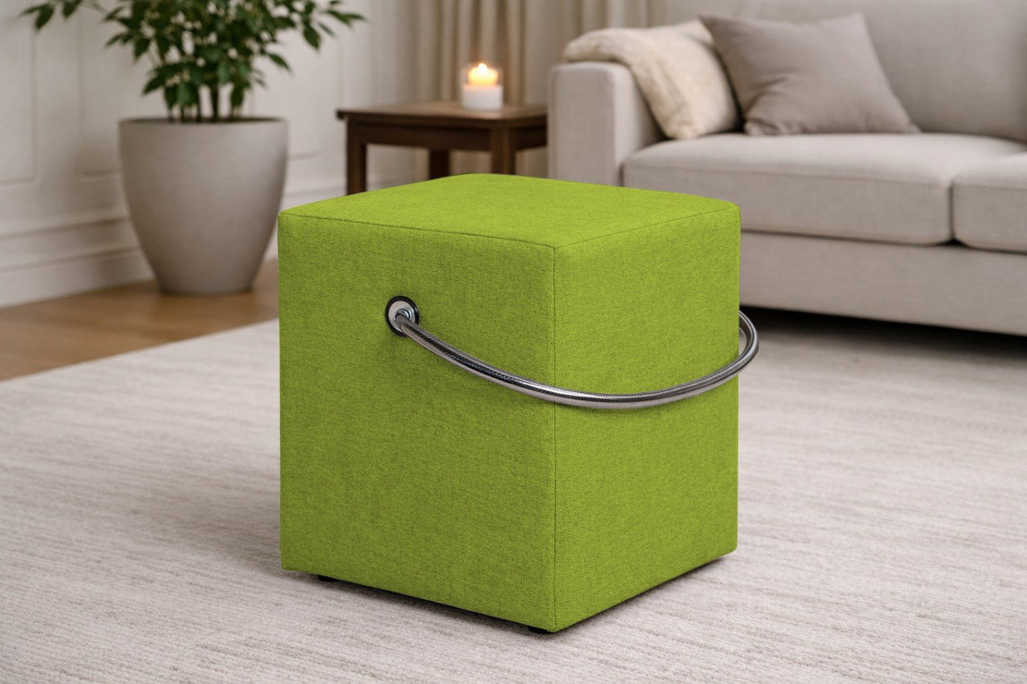 Grüner Polsterhocker mit Griff im modernen Wohnzimmer, leichter Sitzhocker auf hellem Teppich vor Sofa und Beistelltisch.– Handgefertigte Polsterhocker