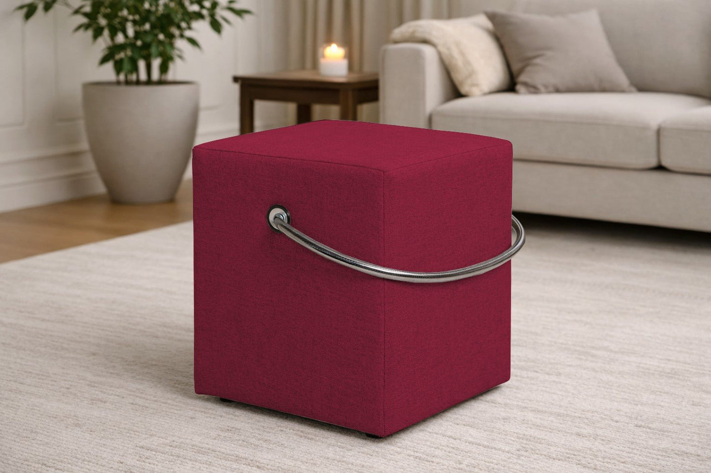 Roter Polsterhocker mit Griff im modernen Wohnzimmer, leichter Sitzhocker auf hellem Teppich vor Sofa und Beistelltisch.– Handgefertigte Polsterhocker