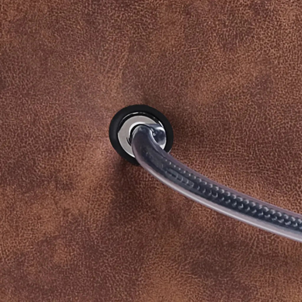 Detailaufnahme des Tragegriffs eines braunen Polsterhockers in Lederoptik mit Metallöse und stabiler Befestigung