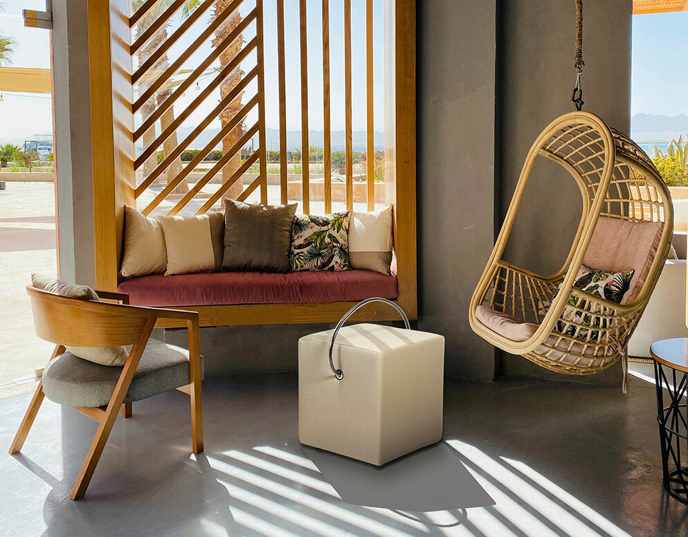 flexibler und bequemer, leichter handgefertigte gepolsterter Sitzwürfel in smartem Design mit Tragegriff auf einer sonnigen terrasse